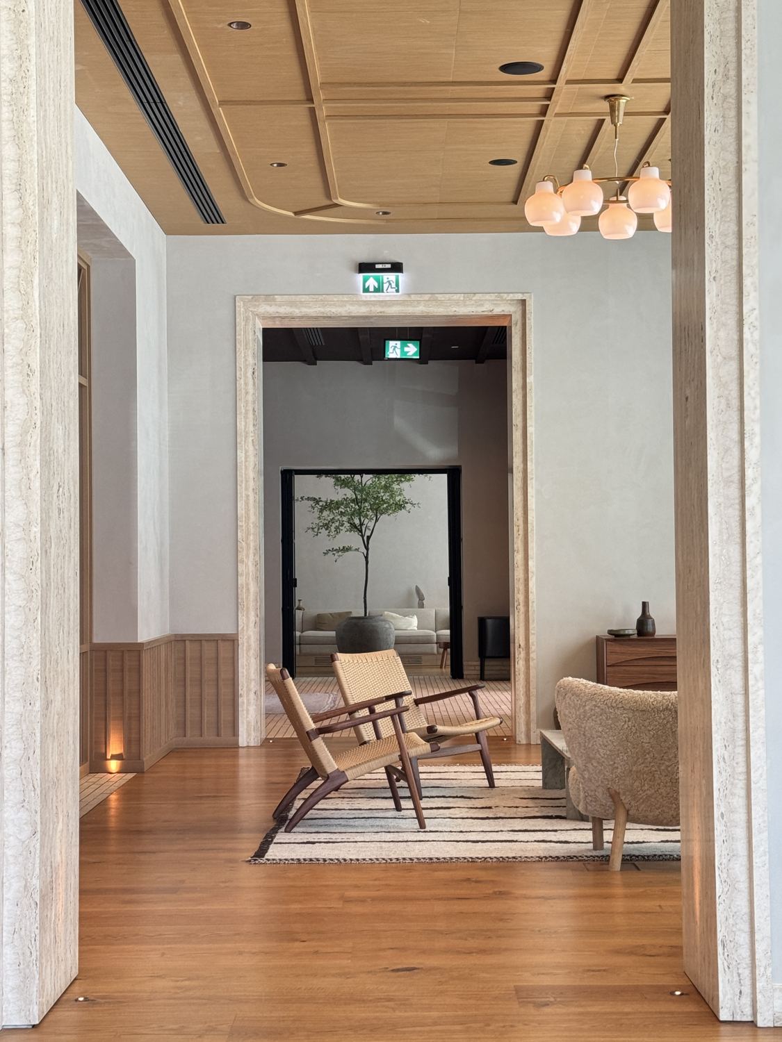Lounge with travertine door frames, oak ceiling, rope chairs and a striped rug