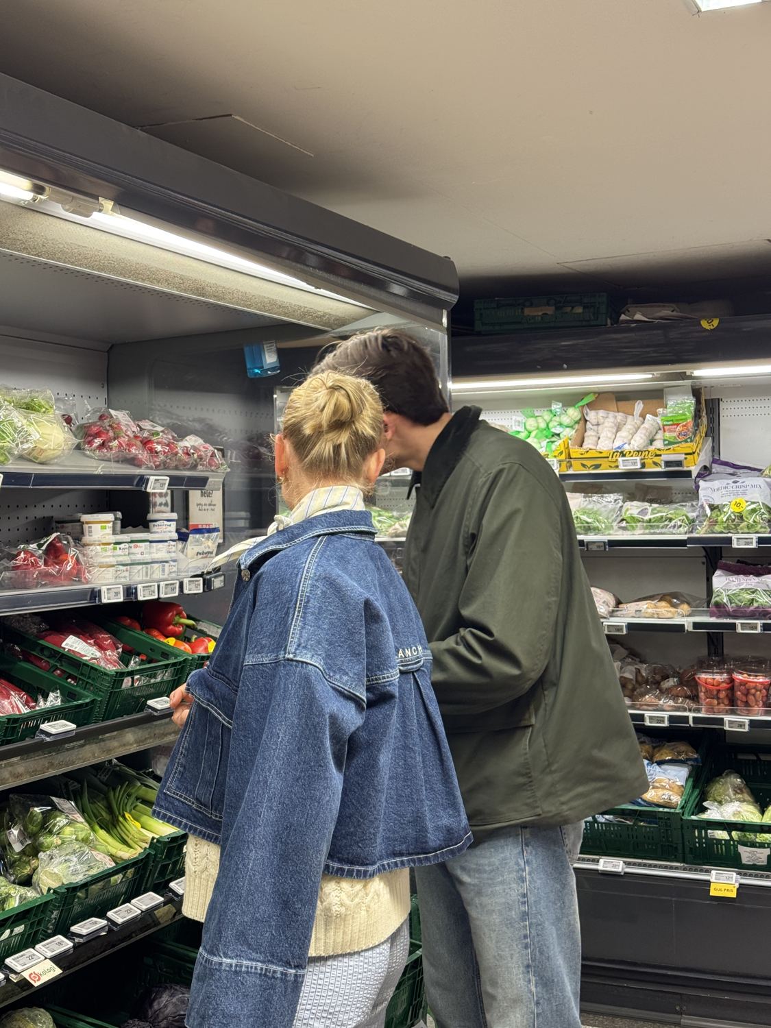 A couple choosing vegetables in a small Copenhagen grocery shop